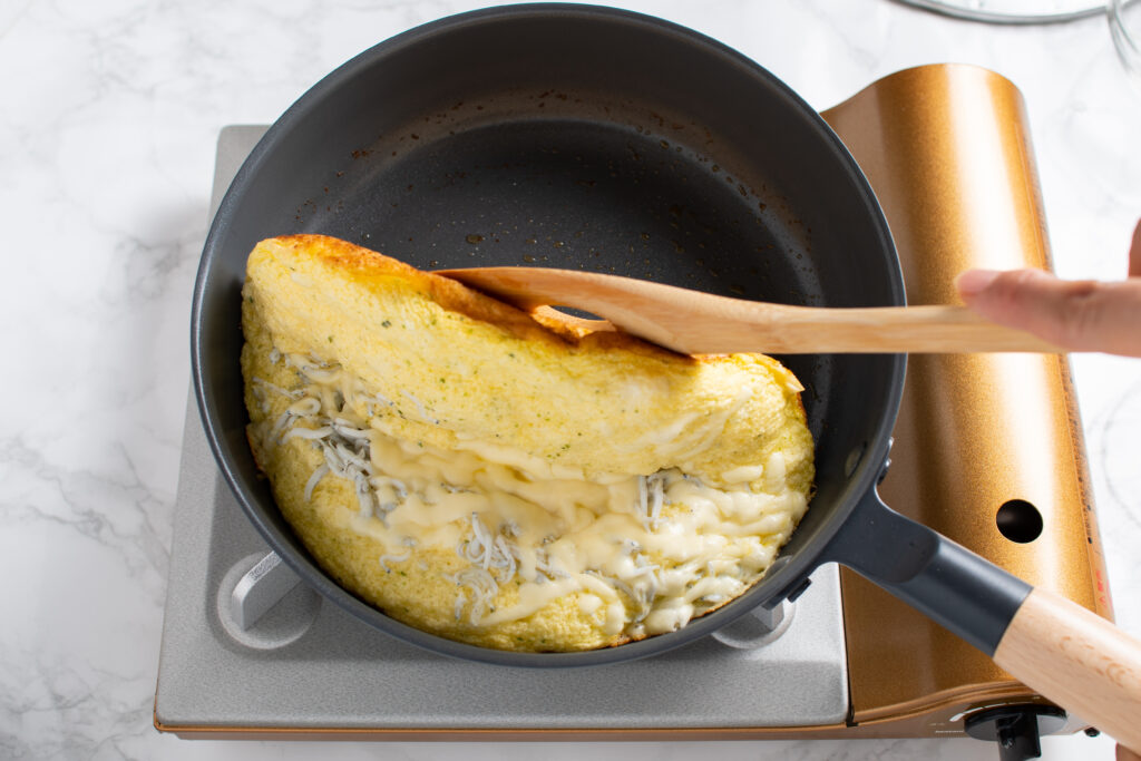 チーズが溶けて裏が淡いきつね色になったら半分に折る。